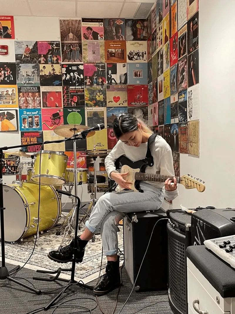 Novia playing guitar in a practice room